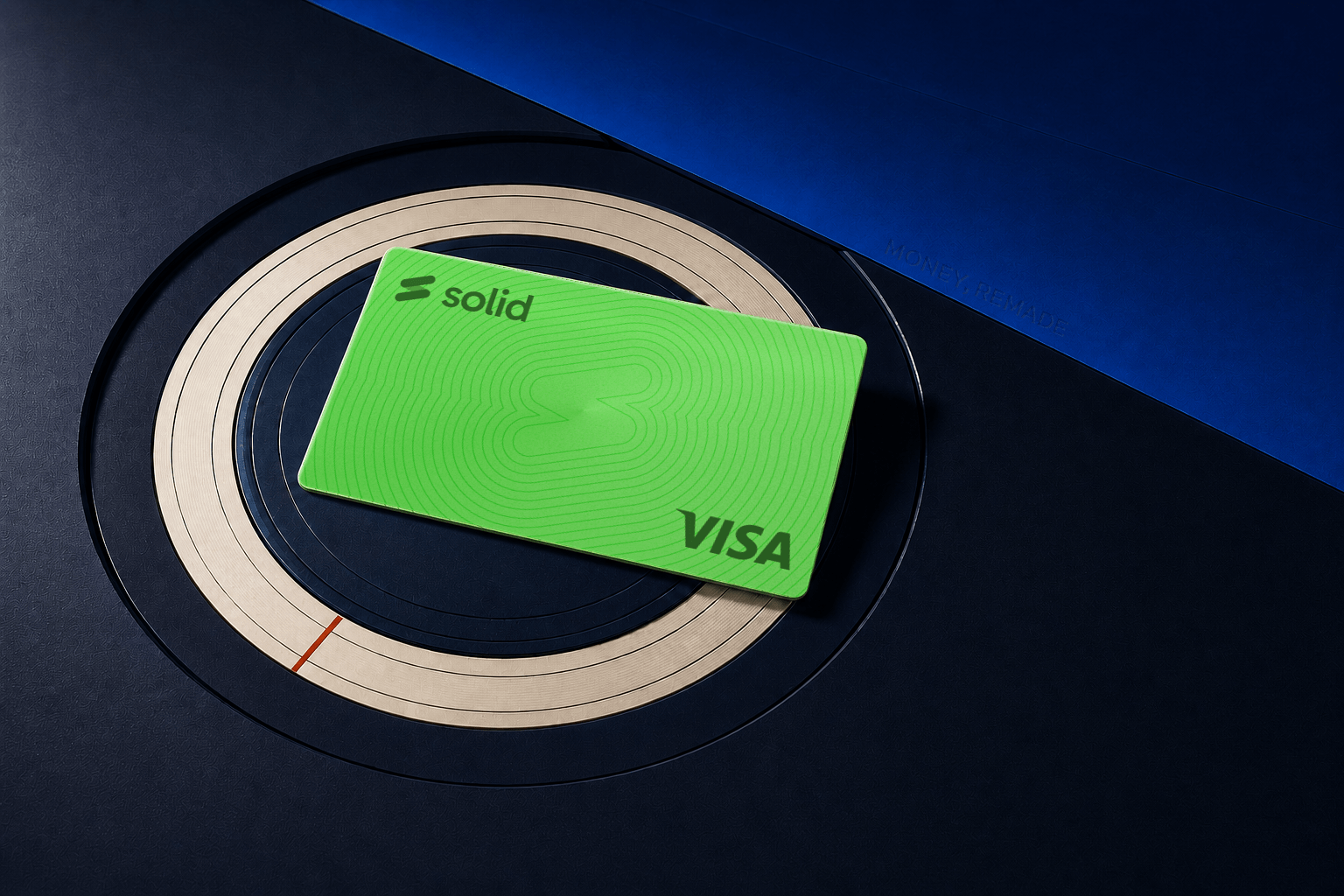 Solid virtual Visa card resting in perspective on a circular ivory and ink editorial instrument, with Money, Remade blind-debossed into the cobalt folio beside it